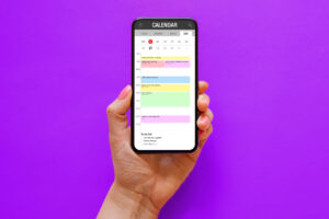 Person holding phone with calendar app on the screen