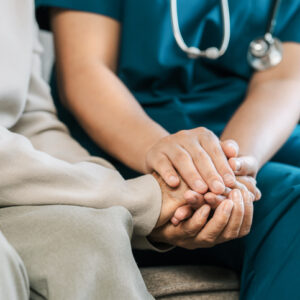 A female nurse caregiver holds hands to encourage and comfort an elderly woman. For care and trust in nursing homes for people of retirement age Caregiver helping elderly woman provides medical advice