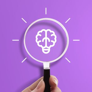 Hand holding magnifying glass with light bulb and brain icon, symbol of psychology and brainstorming.